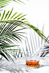 Enjoying rich flavors of scotch whiskey surrounded by refreshing palm leaves in a bright, natural...