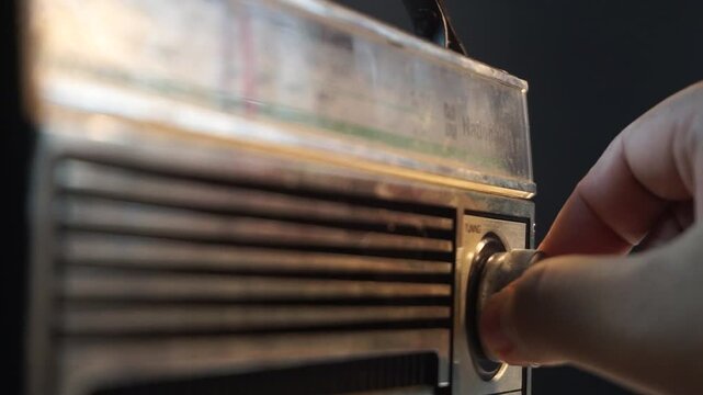 Classic radio being tuned with camera focusing on tuning knob, warm lighting adds atmosphere, perfect for retro tech, sound adjustment, or vintage themes