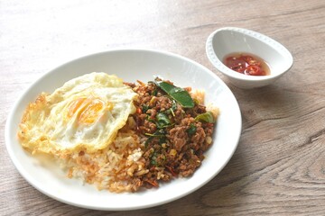 spicy fried chop meat in herb curry topping on plain rice with egg on plate dressing chili fish sauce 