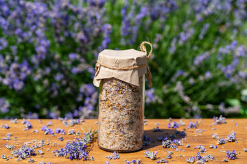 Sea himalayan salt with dry lavender and chamomile flowers in a glass jar against lavender flowers...