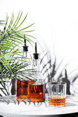 Two elegant bottles of Japanese single malt whiskey beside a glass, surrounded by tropical leaves,...