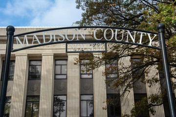 The photo capturing the entrance sign of Madison County Courthouse in Jackson, Tennessee, classic architecture with grand columns and autumn trees frames this historic government building beautifully