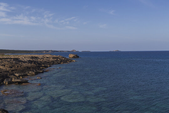 View of the rugged coastline meeting the turquoise sea under a vast blue sky with scattered clouds, a serene seascape, Dipkarpaz, Northern Cyprus, Cipro.