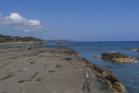 View of rugged, sun-baked rocks meet the turquoise sea under a clear blue sky, creating a serene coastal landscape, Dipkarpaz, Northern Cyprus, Cipro.