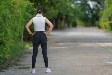 A woman in sportswear running in the park, enjoying fresh air, engaging in outdoor activities to...