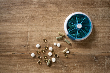Diverse assortment of vitamins and supplements arranged on a wooden surface in a natural light...