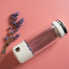 Stylish water bottle rests on a soft pink background, accompanied by fresh lavender sprigs, perfect...