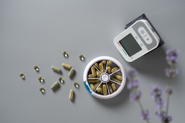 Daily wellness routine with herbal capsules and health monitor on a calming gray surface surrounded...