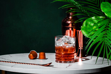Iced Caramel Coffee alcoholic cocktail drink with vodka, cold coffee and ice. Green background,...