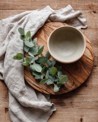 Natural materials create a calming tabletop arrangement with a bowl, leaves, and linen cloth in soft earth tones