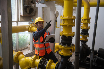 An engineer is inspecting a pressure motor pump and checking a gas pipeline pressure gauge