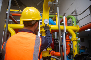 Engineer is checking pressure gauges on gas pipelines in a large factory