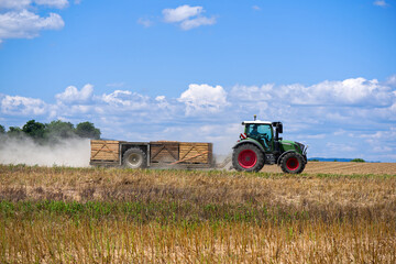 Side view of tractor with trailer crossing agriculture field at Swiss village of Oberglatt on a...