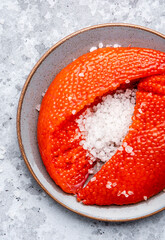 Fresh whole raw red caviar extracted from live trout or salmon with sea salt, grey background, top view