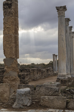 View of weathered stone columns rise against a dramatic sky, casting long shadows across the ancient ruins, Salamis Harabeleri, Harabeleri Salamis Yolu, Cipro.