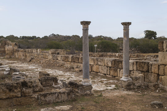 View of weathered columns stand amidst the crumbling stone ruins, whispering tales of a forgotten era under a soft sky, Salamis Harabeleri, Harabeleri Salamis Yolu, Cipro.