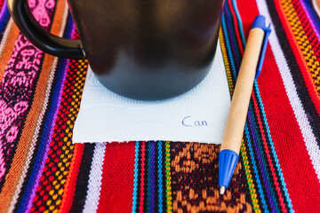 Coffee cup with a note written that says you can do it on a colorful Inca woven table