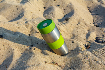 Camping lantern partially buried in sand creating mysterious glowing effect on beach