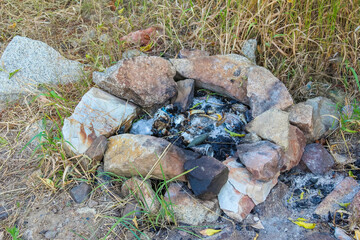 Stone campfire ring with charred remains surrounded by rocks creating outdoor camping scene