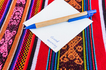 Coffee cup with a note saying good morning on a colorful table with Inca weave.