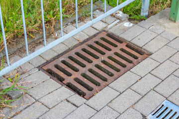 Metal storm drain grate set into concrete paved surface for urban water management system
