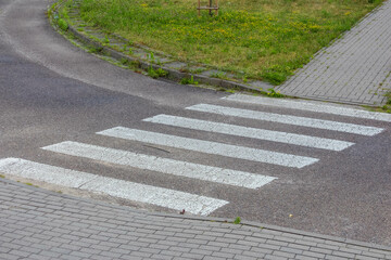 White painted crosswalk stripes on gray asphalt road surface creating pedestrian crossing pattern