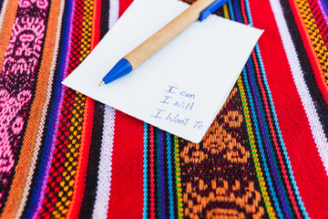 Coffee mug with a note written on it that says I can do it I want to on a colorful table with Inca...