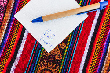Coffee mug with a note written on it that says I can do it I want to on a colorful table with Inca...