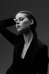 Black and white portrait of a young woman in a blazer with closed eyes and relaxed expression,...