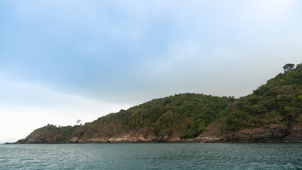 Fototapeta premium Part of the island area is the tip of the land that protrudes from the sea floor. Full of rocks and green forest floor. Under the sky. and foreground of ocean.