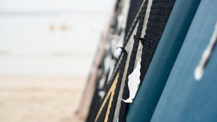 Abstract background of old surfboard. Leaning against the blurry beach and showing bright sunlight.