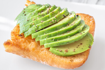 Toasted ciabatta sandwich with sliced avocado served on a clean plate