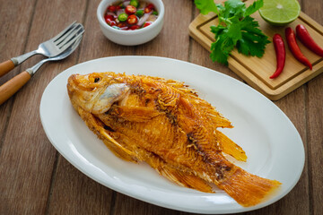 Deep fried red tilapia fish on white plate and dipping sauce