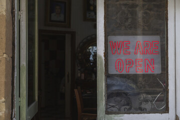Lefkosia, Cyprus - 25 June 2025: View of the neon 'WE ARE OPEN' sign glows warmly against the weathered door, hinting at the inviting atmosphere within..