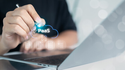Close-up of a hand pointing to a PaaS cloud icon on a laptop screen, symbolizing platform as a...