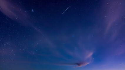 Obraz premium A shooting star streaks across the deep blue night sky filled with countless stars