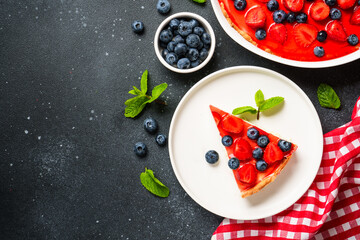 Tart with strawberry and blueberry and jelly. Top view on black background.