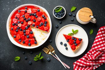 Tart with fresh berries and jelly. Top view on black background.