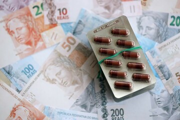 Brazilian reais banknotes and medicine pills. Brazil real money and drugs lies on table