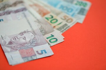 Close up of brazilian reais money bills in big amount on red. Pile of Brazil real currency banknotes
