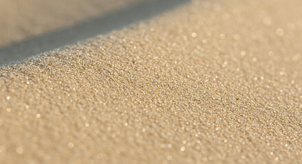 Close-up view of textured sand, highlighting tiny grains and subtle light.