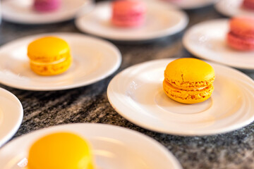Yellow and red sweet macaroons on the table on a white plate. Luxurious baked cakes at a celebration
