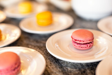 Yellow and red sweet macaroons on the table on a white plate. Luxurious baked cakes at a celebration
