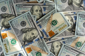Pile of 100 dollar bills scattered on wooden table under sunlight. Concept of cash money, savings,...