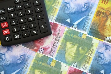 Swiss franc banknotes and calculator. The francs money bills and calc lies on table