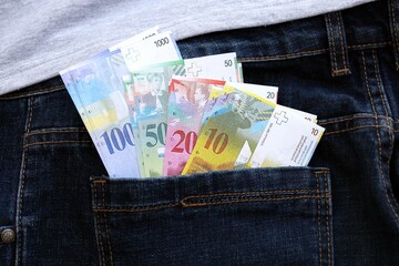 Swiss franc banknotes in denims pocket. The current francs money bills lies in jeans pocket