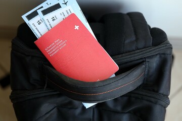 Swiss passport and avia tickets on travel bag. Pass and boarding tokens on bag close up