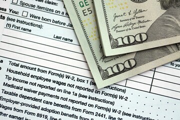 Hundred dollar bills and 1040 individual income tax return form blank close up