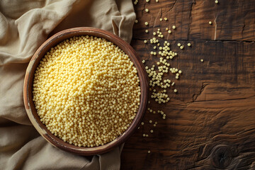 couscous groat raw in bowl on wooden countertop, top view