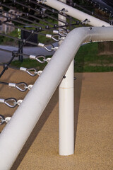 Modern playground climbing net structure and bike rack in a green city park at sunset. Urban recreational area for children and adults